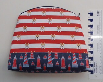 May include: A red and white striped zippered pouch with a pattern of cartoon corgis. The bottom of the pouch has a blue and red lighthouse pattern.