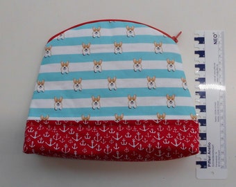 May include: A red and blue zippered pouch with a pattern of white stripes and small dog faces on the top half and red anchors on the bottom half.