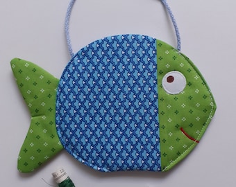 May include: A green and blue fabric fish with a white eye and a red mouth. The fish has a loop for hanging and is accompanied by two spools of green thread.