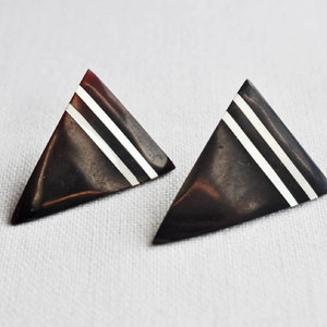 May include: A pair of triangle-shaped earrings with a black and white geometric design.