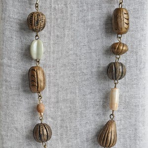 May include: A necklace with brown and beige beads, including a long, cylindrical bead with a gray and white pattern.