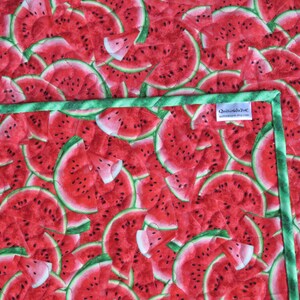 Puede incluir: Una tela acolchada verde y blanca con estampado de sand&iacute;a. La tela presenta un patr&oacute;n repetitivo de rodajas de sand&iacute;a rojas con semillas negras.