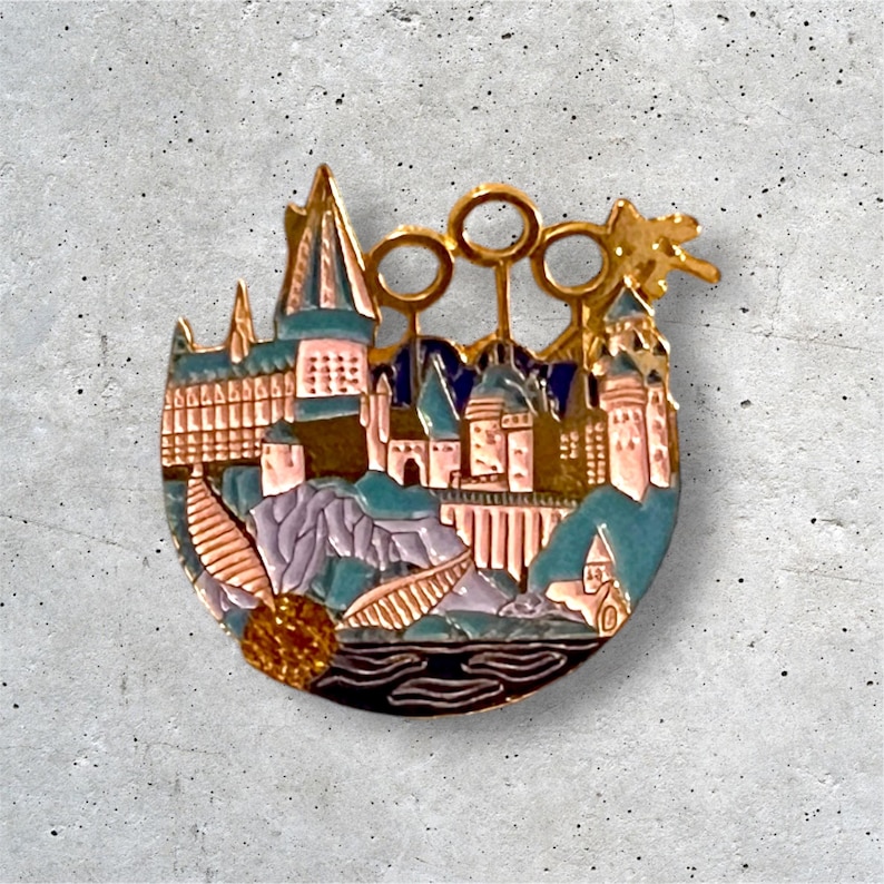 K&ouml;nnte beinhalten: Eine goldfarbene Emaille-Anstecknadel, die Hogwarts Castle darstellt, die legend&auml;re Schule f&uuml;r Hexerei und Zauberei aus der Harry-Potter-Reihe. Die Anstecknadel zeigt eine detaillierte Darstellung des Schlosses, einschlie&szlig;lich seiner T&uuml;rme, Fenster und des Gel&auml;ndes. Die Anstecknadel enth&auml;lt auch eine Darstellung des Goldenen Schnitzers, eines magischen Objekts, das im Sport Quidditch verwendet wird.