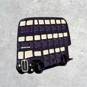 K&ouml;nnte beinhalten: Eine lilafarbene Doppeldeckerbus-Enamel-Anstecknadel mit wei&szlig;en Fenstern und dem Schriftzug "Knight Bus" an der Seite.