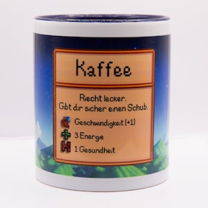 Może przedstawiać: Biały kubek do kawy z niebieskim rantem. Kubek przedstawia pikselową grafikę karty przedmiotu z gry wideo z tekstem "Kaffee" i statystykami prędkości, energii i zdrowia.
