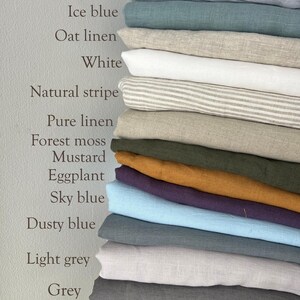 May include: A vertical stack of folded fabric swatches in various colors and patterns, including grey stripes, ice blue, oat, white, natural stripe, pure linen, forest moss, mustard, eggplant, sky blue, dusty blue, light grey, grey, and black.