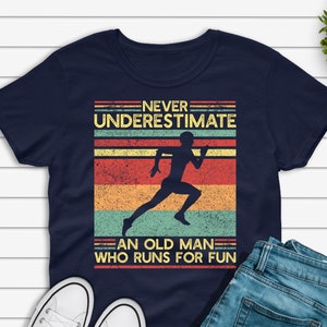 Könnte beinhalten: Ein marineblaues T-Shirt mit einer Grafik im Vintage-Stil eines Läufers. Die Grafik lautet "Never underestimate an old man who runs for fun".
