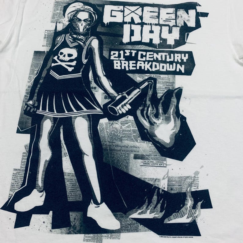 K&ouml;nnte beinhalten: Wei&szlig;es T-Shirt mit einem schwarz-wei&szlig;en Grafikdesign einer Figur in einem Cheerleader-Outfit, die einen Molotowcocktail h&auml;lt. Der Text "GREEN DAY" und "21st CENTURY BREAKDOWN" sind ebenfalls zu sehen. Das Design beinhaltet einen Totenkopf und gekreuzte Knochen.