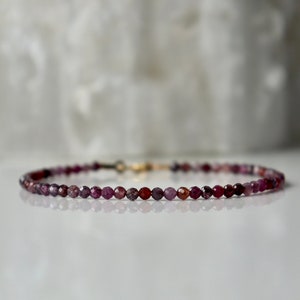 Peut inclure: Un bracelet délicat composé de petites perles rondes de pierres précieuses roses et rouges. Le bracelet est doté d'un fermoir en or.