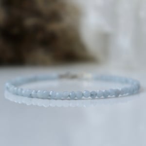 Könnte beinhalten: Ein zartes Armband aus hellblauen Edelsteinperlen. Das Armband ist auf einer silbernen Kette aufgefädelt.