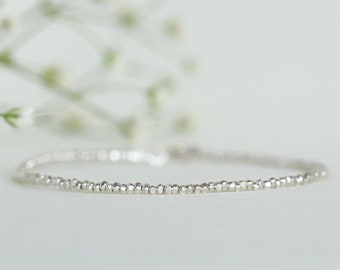 Könnte beinhalten: Ein zartes silbernes Armband aus winzigen Perlen. Das Armband ist schlicht und elegant und perfekt für den Alltag.
