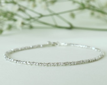 Könnte beinhalten: Ein zartes silbernes Armband aus winzigen Perlen. Das Armband ist schlicht und elegant und perfekt für den Alltag.