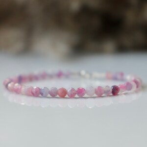May include: A delicate bracelet made with small, faceted, pink and purple gemstone beads.