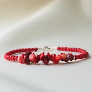 May include: A red coral beaded bracelet with a silver clasp and larger red coral stones.