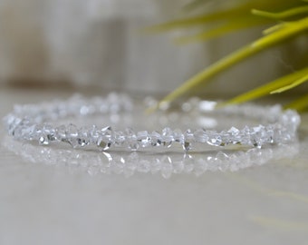 Puede incluir: Un delicado brazalete hecho de cuentas de cristal transparente y facetadas. El brazalete está enhebrado en una fina cadena de plata y es perfecto para añadir un toque de brillo a cualquier atuendo.