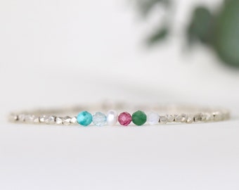 May include: A delicate silver bracelet featuring a row of colourful gemstone beads. The beads are turquoise, light blue, white, pink, green, and white.