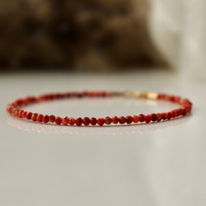 Puede incluir: Un delicado brazalete de piedras preciosas rojas con peque&ntilde;as cuentas redondas. El brazalete est&aacute; hecho con un cierre de oro.