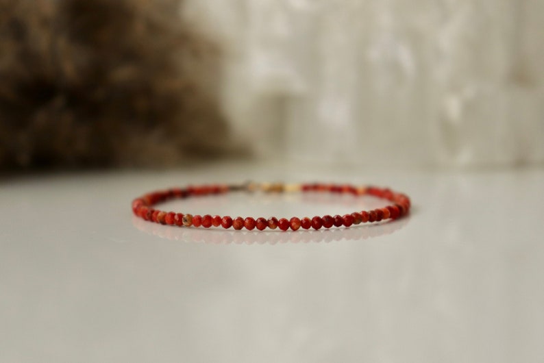 Puede incluir: Un delicado brazalete de cuentas de coral rojo con cierre dorado.