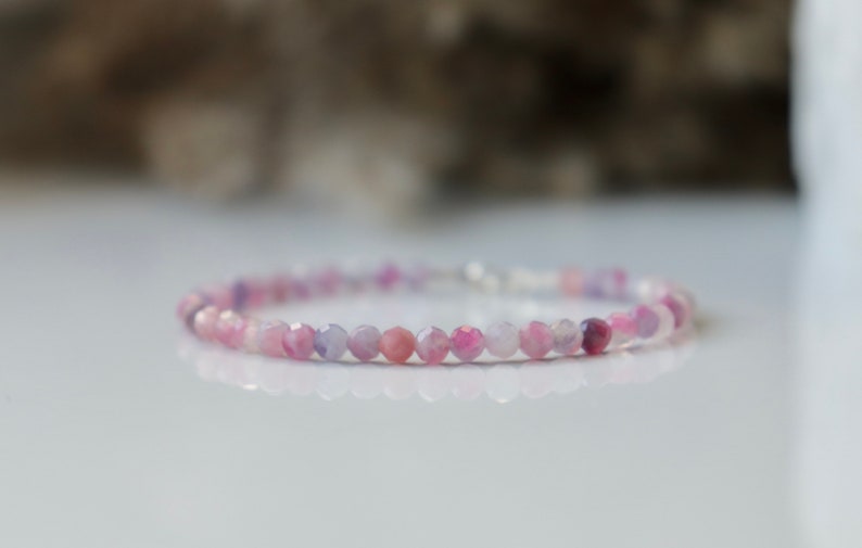 May include: A delicate bracelet made with small, faceted, pink and purple gemstone beads.
