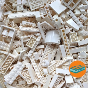 May include: A large pile of white LEGO bricks of various shapes and sizes. The bricks are arranged in a random pattern, and some of them are stacked on top of each other. The bricks are all made of a smooth, white plastic. The text "BUILD CREATIVELY" is visible on a small orange circle in the lower right corner of the image.