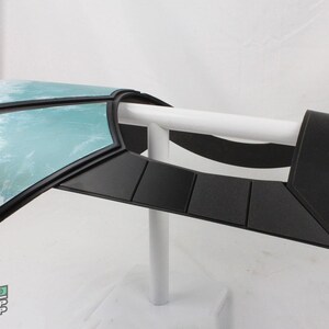 May include: A prop piece with a black frame and a light blue, textured panel. The piece is mounted on a white support, and the Neo Prop Shop logo is visible in the lower left corner.