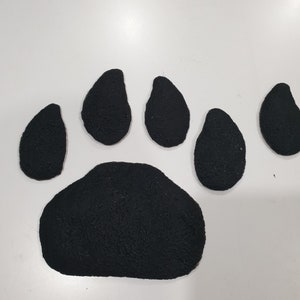 Puede incluir: Huella de pata de fieltro negro con cinco dedos. La huella de pata est&aacute; hecha de cinco piezas de fieltro separadas.