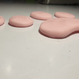 K&ouml;nnte beinhalten: Ein rosa Pfotenabdruck aus weichem, weichem Material. Der Pfotenabdruck besteht aus f&uuml;nf einzelnen Pads.