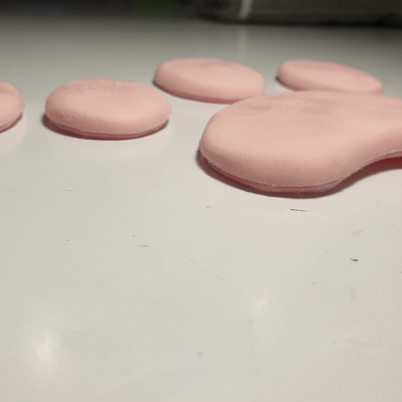 K&ouml;nnte beinhalten: Ein rosa Pfotenabdruck aus weichem, weichem Material. Der Pfotenabdruck besteht aus f&uuml;nf einzelnen Pads.