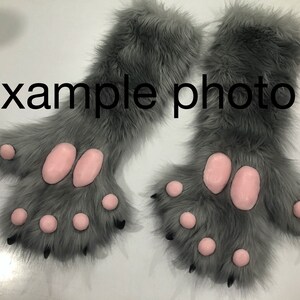 May include: A pair of gray furry paws with pink paw pads and black claws. The paws are attached to furry gray sleeves.
