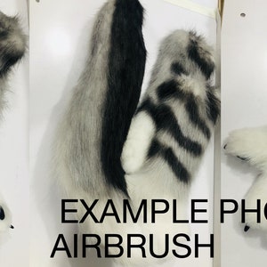 May include: A pair of white and gray furry paws with black claws. The paws have a striped pattern and are attached to furry arms. The image includes the text "EXAMPLE PHOTO AIRBRUSH".