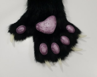 May include: Black furry paw with five purple paw pads and white claws.