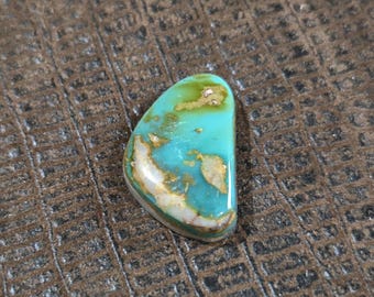 May include: A turquoise cabochon with a green, white, and brown matrix. The stone is irregularly shaped and has a smooth, polished surface.