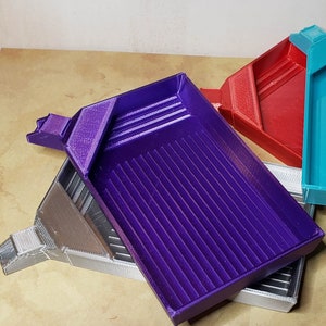 May include: Four plastic gold panning trays in different colors: purple, gray, red, and turquoise. The trays are stacked on top of each other.