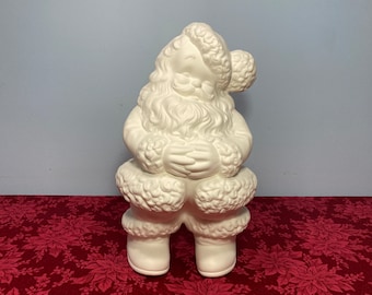 May include: White ceramic Santa Claus figurine with a fluffy beard and hat. He is holding his hands together in front of him and is wearing a fur-trimmed coat and boots.