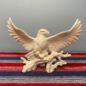 May include: White ceramic bald eagle figurine with outstretched wings perched on a branch. The eagle is a popular symbol of freedom and strength.