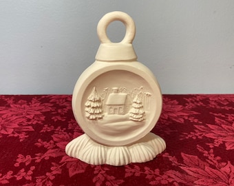 May include: White ceramic Christmas bauble shaped like a round ball with a small house and trees in a snowy scene. The bauble has a loop at the top for hanging.