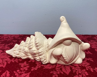 Peut inclure: Figurines de gnome en céramique blanche avec un chapeau pointu et une barbe. Le gnome tient un sapin de Noël dans ses bras.