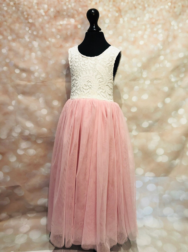 Puede incluir: Un corpi&ntilde;o de encaje blanco con una falda de tul rosa. El vestido es sin mangas y tiene un escote redondo. El vestido est&aacute; en un maniqu&iacute;.