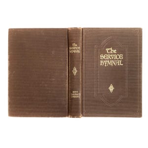 May include: An open brown book titled "The Service Hymnal" with gold lettering. The book is displayed open, revealing the spine and cover. The spine reads "The Service Hymnal" and "Hope Publishing Company".