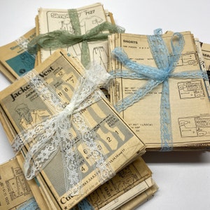 May include: Stacks of vintage sewing patterns tied with lace ribbons in shades of white, blue, and green. The patterns feature illustrations of clothing items like jackets, vests, and shorts, with size and measurement details.