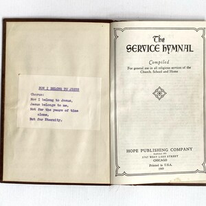 May include: An open book titled "The Service Hymnal" with a brown cover. The title page includes the text "Compiled" and "For general use in all religious services of the Church, School and Home." A smaller page has the text "How I Belong to Jesus."