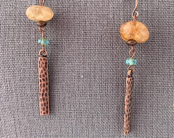 May include: A pair of dangle earrings with a copper hammered bar, a light brown bead, and a light blue crystal bead.