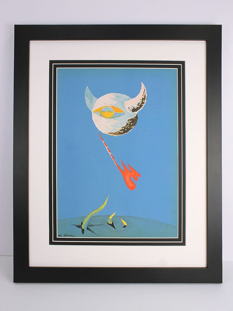 Puede incluir: Una impresi&oacute;n enmarcada de una pintura surrealista que presenta un orbe blanco con un ojo grande y cuernos sobre un fondo azul. El orbe flota sobre un paisaje con formas abstractas rojas y amarillas.