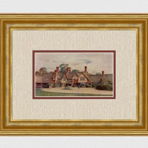 May include: A framed print of a watercolor painting depicting a row of Tudor-style buildings with red brick chimneys and thatched roofs. The print is set within a gold-colored frame and a cream-colored mat.