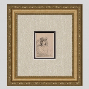 May include: A framed portrait of a person wearing a hat and coat. The artwork is a sketch in black and white, set against a beige background. The frame is gold with ornate detailing.