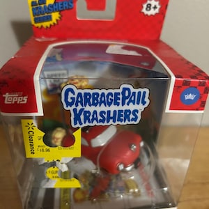 May include: A red and white Garbage Pail Krashers "Blasted Billy" figure in a clear plastic case. The box is red with yellow accents and features the text "All-New Krashers Series" and "Ages 8+". The Topps brand is visible.