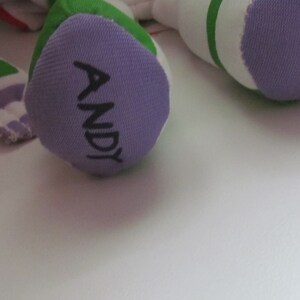 May include: Purple fabric foot of a plush toy with the name "ANDY" written in black.