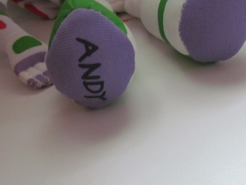 May include: Purple fabric foot of a plush toy with the name "ANDY" written in black.