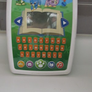 May include: White and green LeapFrog educational tablet toy with colorful animal illustrations and an alphabet keyboard. Features a screen and buttons with letters and symbols. Designed for early learning.