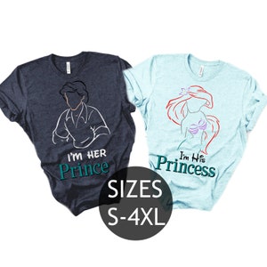 Può includere: Due magliette con un design di coppia. La maglietta blu ha un contorno bianco del principe Eric de La Sirenetta con il testo "I'm Her Prince". La maglietta azzurra ha un contorno bianco di Ariel de La Sirenetta con il testo "I'm His Princess". Il testo "SIZES S-4XL" è stampato sotto le magliette.